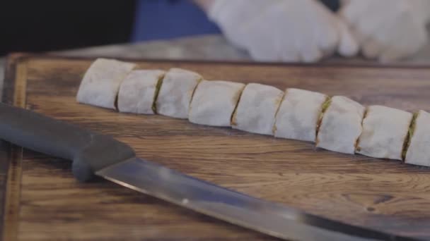 Close-up van kebab verpakt in pita lavash gesneden in stukken liggen op tafel. Grote scherp mes is in de buurt. Camera beweegt juiste — Stockvideo