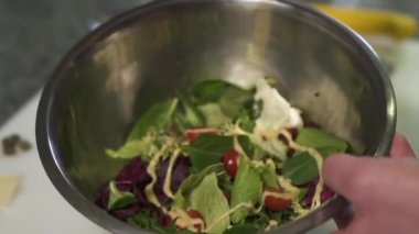 Büyük alüminyum kase salata dökülen domates ile holding Şef eller, ıspanak ve fesleğen Sarı sos ile kapatın. Mutfakta yiyecek hazırlama Cook. Sağlıklı yaşam tarzı