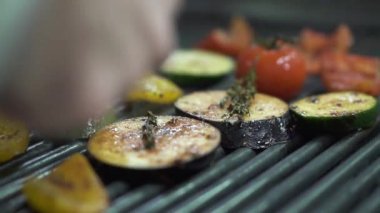 Şef el kontrol sebze domates, patlıcan, kabak, sarı dolmalık biber ızgara metal maşa kullanarak kapatın. Cook vejetaryen yemek hazırlanıyor. Sağlıklı yaşam tarzı