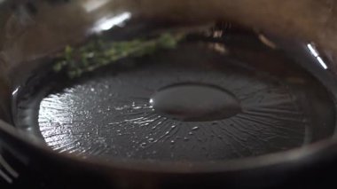 Otlar görünümü kapatın ve zeytin yağı kızartma tavası, Şef üzerinde sarımsak parçası ekler. Modern restoranda vejetaryen yemek hazırlama Cook. Sağlıklı yaşam tarzı