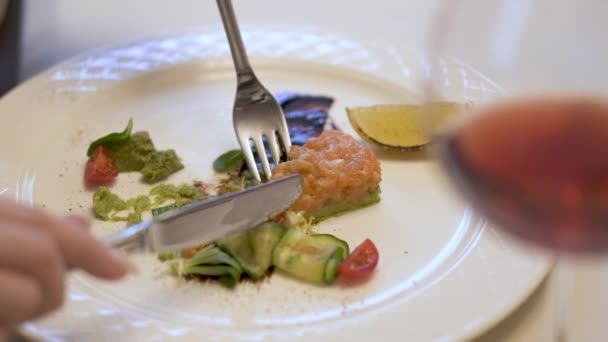 Prato branco com torta de peixe de salmão moído e abacate com salat verde fresco. Mãos de mulheres com garfo e faca gentilmente obter salmão no garfo . — Vídeo de Stock