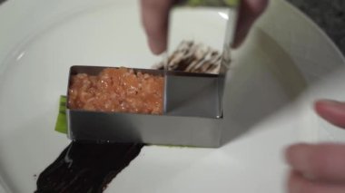 Modern restoranda Şef elleri basarak ve kıyılmış somon küçük metal kalıp kullanarak şekli oluşturan kapatalım. Yemek hazırlama balık yemi. Ağır çekim