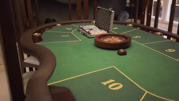 Крупный план игрового стола с зеленой поверхностью с покером установлен на нем в современном казино. Комфортное место с роскошным интерьером, ожидающим гостей — стоковое видео