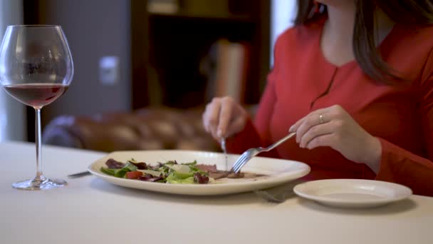 Милая женщина в красном сидит в ресторане и ест вкусный салат — стоковое видео
