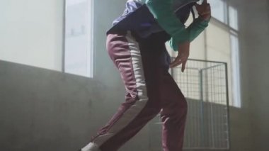 Koyu terk edilmiş binada büyük pencerenin önünde gerçekleştirme deneyimli genç hip-hop sokak dansçısı. Yapma adam taşır, atlama ve dans crouches... Ağır çekim