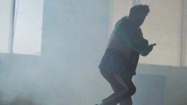 Koyu terk edilmiş binada büyük pencerenin önünde gerçekleştirme yetenekli genç hip-hop sokak dansçısı. Çağdaş. Hip hop kültürü. Prova. Ağır çekim.