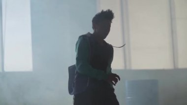 Koyu terk edilmiş binada büyük pencerenin önünde gerçekleştirme deneyimli genç hip-hop sokak dansçısı. Çağdaş. Hip hop kültürü. Prova. Ağır çekim.