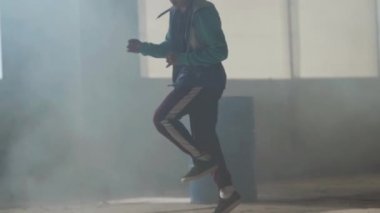 Koyu terk edilmiş binada büyük pencerenin önünde gerçekleştirme yetenekli genç hip-hop sokak dansçısı. Çağdaş. Hip hop kültürü. Prova. Ağır çekim.
