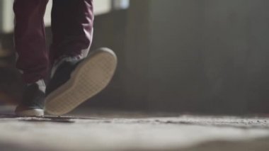 Terk edilmiş bir evde tozlu bir beton zemin üzerinde dans spor ayakkabı içinde profesyonel bir dansçı metrelik.