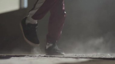 Terk edilmiş bir evde tozlu bir beton zemin üzerinde dans spor ayakkabı içinde uygulanan bir dansçı metrelik.