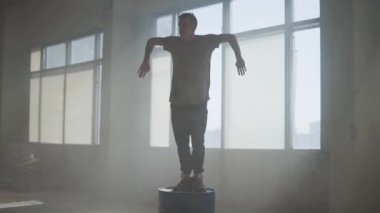 Terk edilmiş bir binada bir varil üzerinde dans sokak dansçısı hip-hop. Çağdaş. Hip hop kültürü. Prova. Ağır çekim.