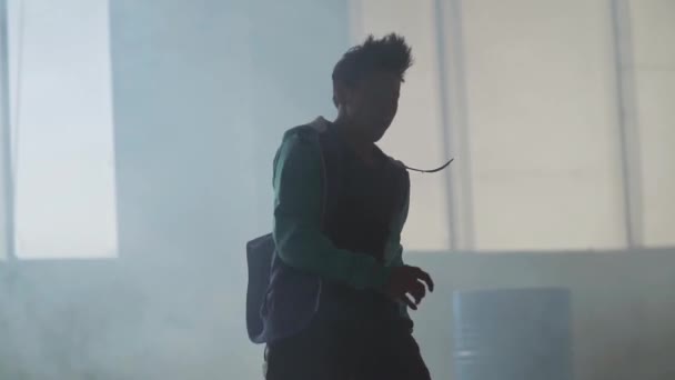 Досвідчений молодий хіп-хоп вуличний танцюрист, який виступає перед великим вікном у темній покинутій будівлі. Сучасний. Культура хіп-хопу. Репетиція. Повільний рух . — стокове відео