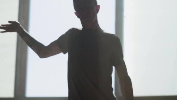 Retrato de un joven y apasionado bailarín de hip-hop actuando delante de la cámara de cerca. El hombre extiende los brazos hacia adelante, luego hace movimientos bruscos a los lados con todo el cuerpo. Ensayo. Movimiento lento . — Vídeo de stock