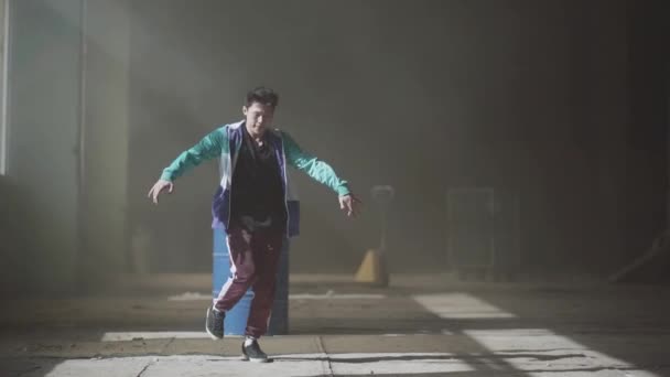 Jonge Aziatische hip-hop mannelijke danser dansen in het donker verlaten gebouw in voorkant van blauwe gas vat. Hedendaagse. Hip hop cultuur. Repetitie. Slow motion. — Stockvideo