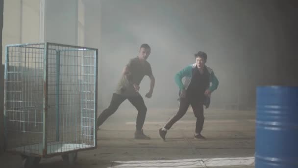 Dva mladí muži tančí v temné a zaprášené místnosti, opuštěné budovy. Přátel v breakdance. Hip hop kultury. Zkouška. Moderní. Zpomalený pohyb. — Stock video