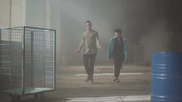 Deux jeunes hommes dansant dans la pièce sombre et poussiéreuse d'un bâtiment abandonné. Les adolescents qui font bouger la danse simultanément, en se tenant la main. Des hommes flexibles qui font des vagues avec leur corps. Mouvement lent — Video