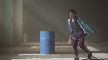 Sisin içinde terk edilmiş bir binada, varil yakınındaki spor genç hip hop dansçı. Hip hop kültürü. Prova. Çağdaş.
