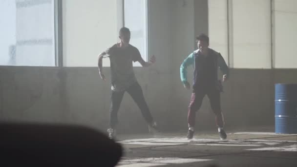 Deux garçons dansant devant la grande fenêtre dans un bâtiment abandonné. Les adolescents qui font bouger la danse simultanément. Les gars qui s'entraînent au breakdance. Culture hip hop. Répétition. Contemporain . — Video