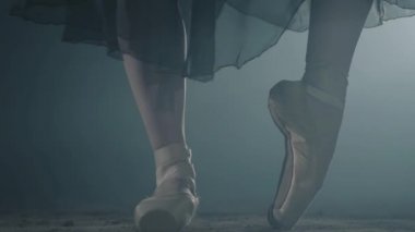 Kadın ince bacaklar poz ayakta ve stüdyoda siyah arka planda adımlar yapmak. Profesyonel Balerin Bale ayakkabıları ve siyah elbise dans. Kapat şunu. Yavaş hareket