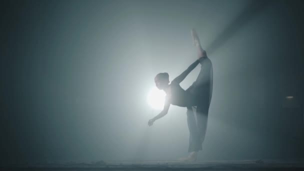 Bailarina de ballet profesional bailando en zapatos de ballet y vestido negro en el estudio en el centro de atención sobre un fondo negro. Joven bailarina elegante realizando elementos de baile de ballet clásico . — Vídeos de Stock