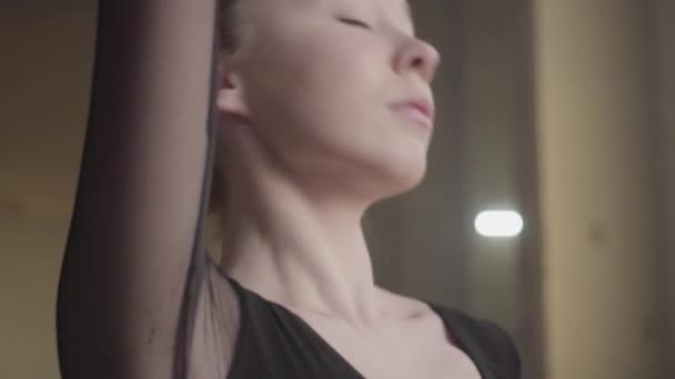 Retrato bailarina profesional bailando en vestido negro en el estudio frente a una gran ventana. Joven hermosa mujer bailarina de pie en puntas de los pies y haciendo pequeños pasos — Vídeo de stock