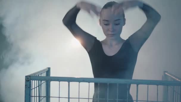 Close up portrait of graceful professional ballerina dancing in black dress in the studio inside the blue cage in spotlight on a black background. Young beautiful woman raising hand standing in a — Stock Video