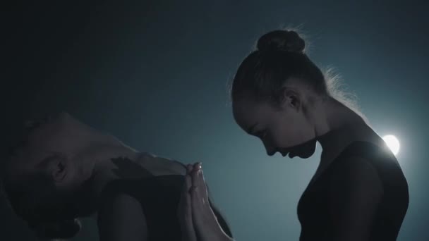 Närbild porträtt två graciösa professionella ballerinor dans element av klassisk balett i mörkret. Balett dansare visar klassiska balett pas i Spotlight på svart bakgrund i studion. — Stockvideo