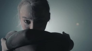 Arka planda ışık ve duman ile karanlıkta siyah bir elbise bir kızın portre yakın. Yüz ve saç genç kadın un.