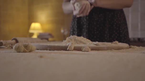 Femme méconnue en robe noire jette la pâte crue dans la farine couchée sur le tableau de la cuisine dans la cuisine. Au ralenti. Gros plan . — Video