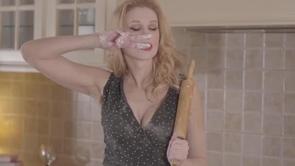 Blonde sexy heiße Frau mit großen Brüsten am Dekollete und Nudelholz auf der Schulter legte Mehllinien auf das Gesicht — Stockvideo