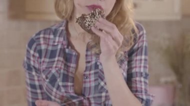 Portre genç güzel sarışın kadın açgözlülükle çörek yeme ve parmaklarını yalama