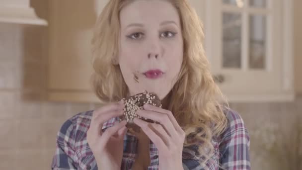 Jeune belle femme blonde avide de manger un beignet et de lécher ses doigts — Video