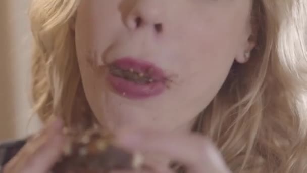 Close-up portret jonge mooie blonde vrouw gretig eten donut en likken haar vingers — Stockvideo