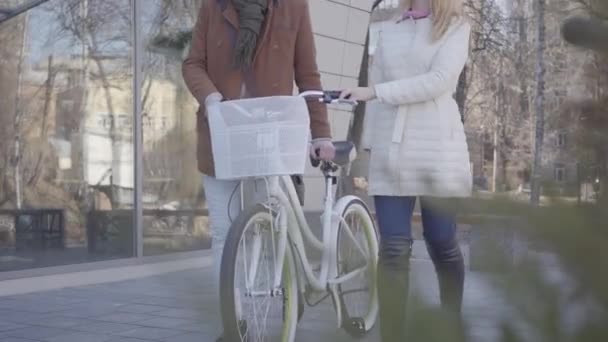 따뜻한 흰색 재킷과 자전거와 거리에서 걷는 갈색 코트에서 키가 큰 남자에서 인식할 수 없는 여자. 젊은 도시 거주자의 레저. 행복 한 부부는 날짜가 있습니다. 활동적인 라이프 스타일 — 비디오