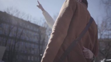 Yakışıklı adam sıcak ceket yüksek binaya bakarak güzel genç sarışın kadın sarılmak. Çift yeni binaya işaret ederek tartışıyor. Yan görünüm. Yavaş hareket