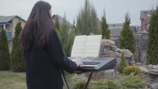 Back view of the young musician in casual closing playing synthesizer. Creativity concept. Real people series. — Stock Video