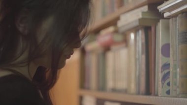 Kütüphanedeki bir kitabı okuyarak parlak makyajla ciddi bir genç öğrencinin portresini kapatın. Çekici genç kız Bookshelf önünde ayakta bir kitap okuyor. Akıllı çekici kadın Leisure