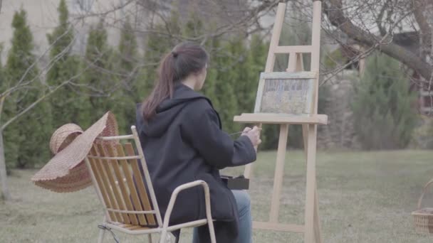 Der gelernte Künstler malt auf der Leinwand im Hinterhof. schöne begeisterte Mädchen in Kreativität engagiert. Inspiration. Talent. — Stockvideo