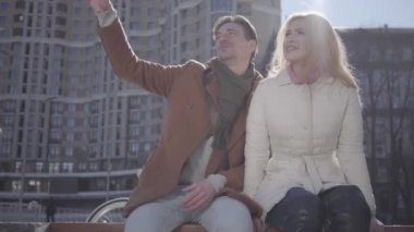 Şehir Caddesi 'nde oturan ve gülümsüyor çekici cuople portresi. Çift birlikte olmaktan zevk tartışmak sohbet