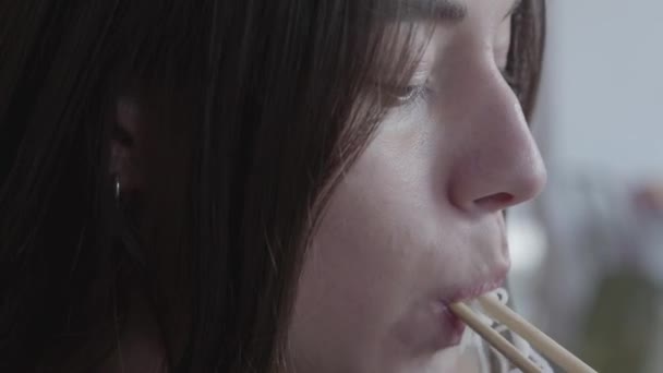 Cerca de la cara de la mujer joven comiendo fideos con palillos de cerca. Cena en restaurante chino. Sabrosa comida saludable apetitosa — Vídeos de Stock