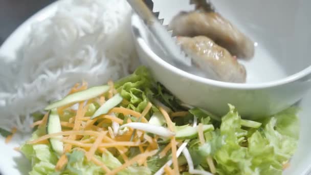 Chef hand puts cutlets in empty bowl standing on the plate near noodles and vitamin salad of carrot, cucumber and lettuce close up. The cook prepares food for serving in the restaurant — Stock Video