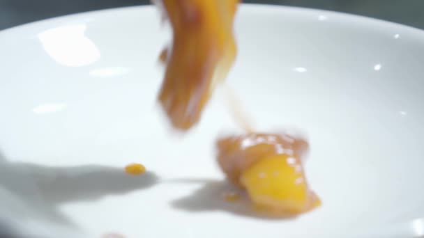 Смачна смажена курка з овочами в медовому соусі падає на тарілку крупним планом. Кухар готує їжу для подачі в ресторані. Курка в кисло-солодкому соусі. Повільний рух — стокове відео