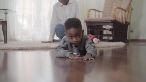 African American mother and little son have fun weekend at home. The boy crawls on the floor and his mother is nearby. Relationship mom and son. A happy family. — Stock Video