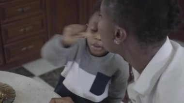 Sevimli Afrikalı Amerikalı kadının küçük oğluyla birlikte masada oturup kurabiyeler ile oynayan portresi. Aile sağlıklı kahvaltı.