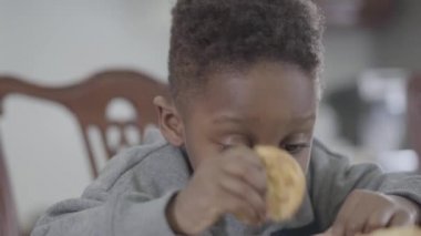 Yemek odasında masada oturan Çerezler ile süt oynarken kirli dudaklar ile sevimli Afrikalı Amerikalı çocuk çocuk portre
