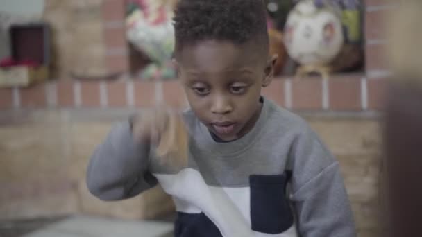 Retrato de niño afroamericano pequeño centrado en jugar y divertirse con juguetes en la sala de estar . — Vídeo de stock