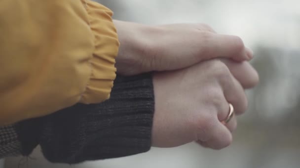 Mężczyzna i kobieta trzymać ręce na zewnątrz na niewyraźne tło. Złoty pierścień jest na palec człowieka. Piękny para w ciepły płaszcze spoczywać razem w Spring Park — Wideo stockowe