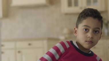 Yakışıklı küçük afro-amerikan çocuk kamera dan yatan ve daha sonra keskin mutfakta yukarı hareket ediyor. Sevimli çocuk gülümsüyor ve mutlu. Çocuk eğlenceli bir ruh halinde