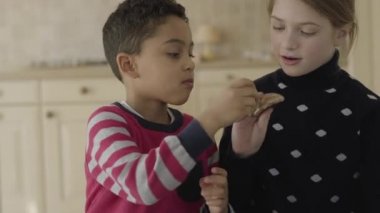 Portre sevimli afrikalı amerikalı erkek ve mavi gözlü sarışın kafkas kız mutfakta oynarken. Kurabiyelerle kavga eden ve sonra tatlı yiyen küçük mutlu arkadaşlar. Komik çocukların boş zamanları