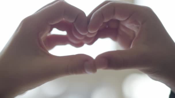Les enfants mignons dépeignent la forme de coeur avec leurs doigts se ferment vers le haut. Coeur formé par des mains d'enfant. Concept d'amour, d'amitié, de paix — Video